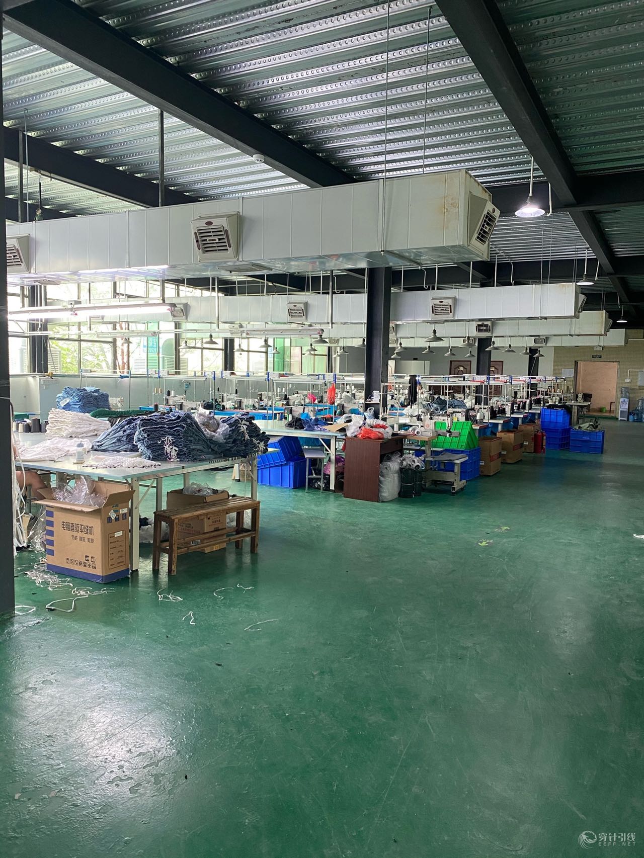 A second view of the factory production area with worktables and denim materials